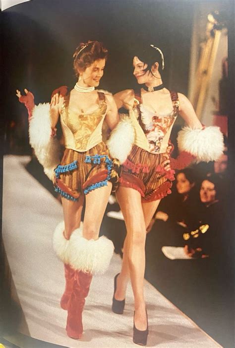 Two Women Walking Down A Runway In Costume