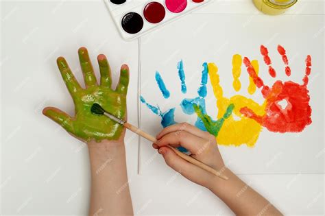 Premium Photo | The child draws his hand with green paint and a brush ...