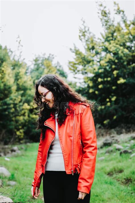 Close Up Of A Smiling Curly Brunette Woman Wearing A Red Leather