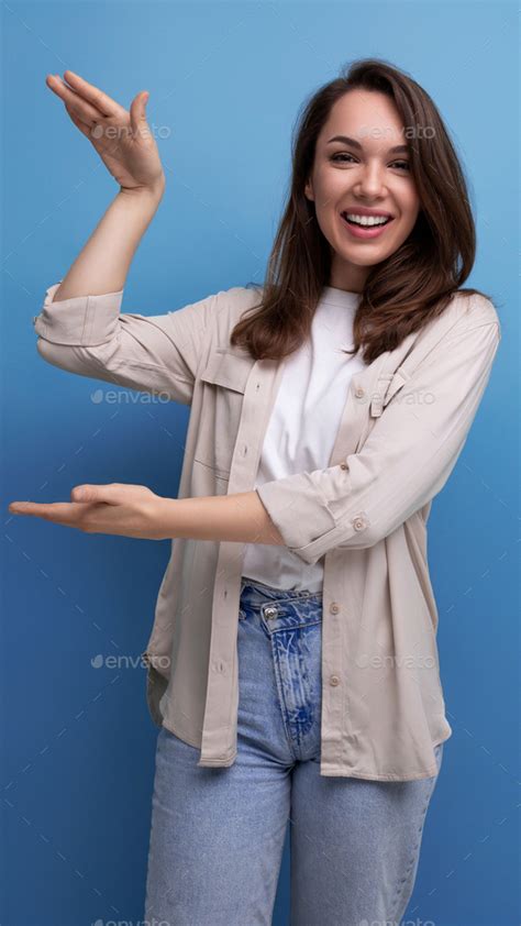 Charming Brunette Year Old Female Person Dressed In A Shirt And Jeans Shows Her Hand At An
