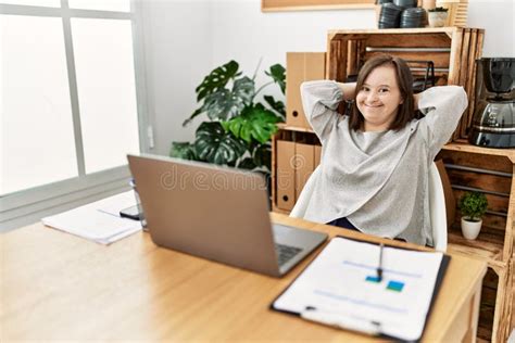 Brunette Woman With Down Syndrome Stretching Arms Relaxing At Business