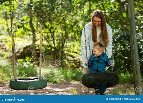 The Mother Is Swinging Her Child On The Swings Stock Photo Image Of