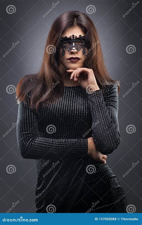 Beautiful Woman With Black Lace Mask Over Her Eyes On The Dark Gray