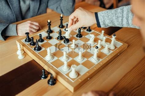 男棋手在棋盘下棋，白骑士拿棋子。国际象棋棋子高清摄影大图 千库网