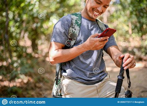 Cropped Image Of A Happy Asian Male Traveler With Trekking Gear Using