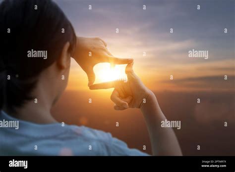 Child girl making frame around the sun with her hands capturing in the ...