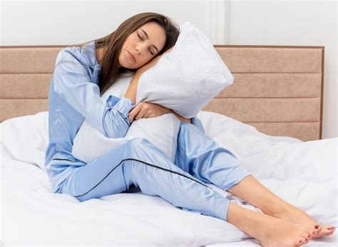 Belle Jeune Femme En Pyjama Bleu Assis Sur Le Lit Avec Oreiller