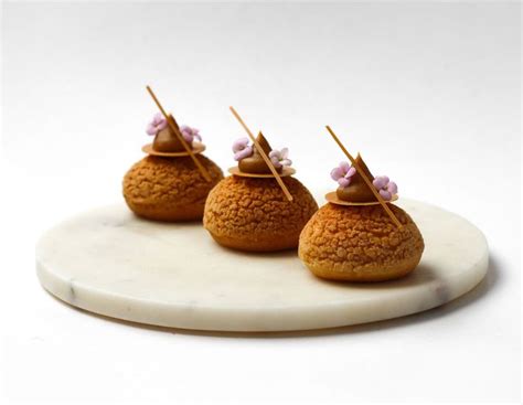 Three Small Desserts On A White Plate With Sticks Sticking Out Of The