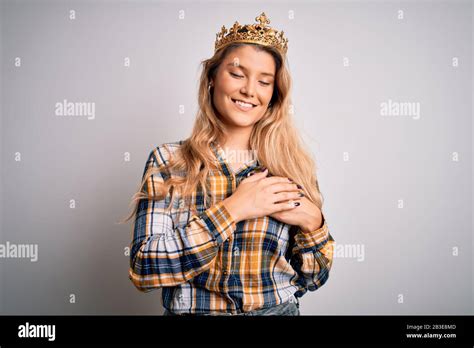Jeune femme blonde portant une couronne dorée de reine sur fond blanc isolé souriant avec des