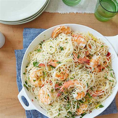 A Bowl Filled With Pasta And Shrimp On Top Of A Wooden Table