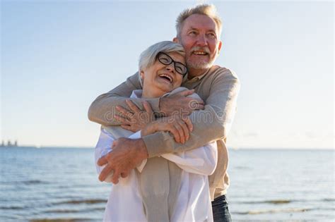 Senior Mature Couple Hugging Enjoying Outdoor Recreation Walking On Beach Old Husband Wife