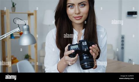 Attractive Smiling Brunette Female Photographer In White Shirt Checking