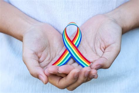 Hand Showing Lgbtq Rainbow Ribbon Against Sky Background In The Morning Support Lesbian Gay