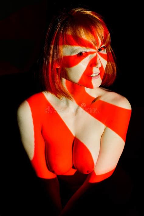 Portrait Of A Beautiful Naked Woman In Red Beams Of The Projector Streaks Of Light And Shadow