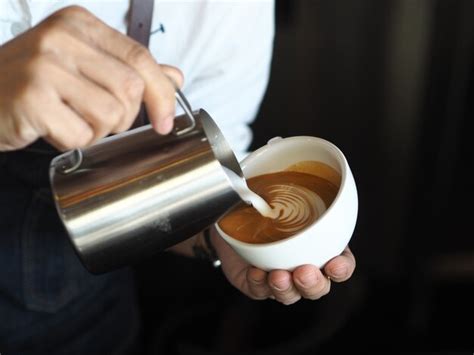 Premium Photo Barista Hands Pouring Warm Milk For Making Coffee Latte