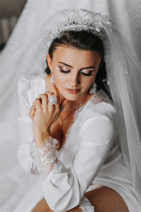 A Brunette Bride Wearing A Lace Dress Poses While Sitting On The Floor Beautiful Hair And Make