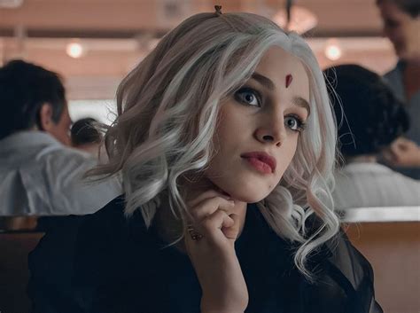 A Woman With Blonde Hair And Blue Eyes Sitting In A Restaurant Looking At The Camera