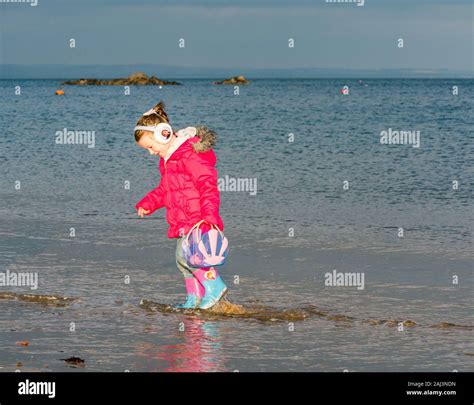 Une Petite Fille Sur La Plage En Hiver Séclabousser Dans La Mer à