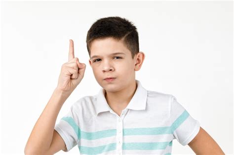 Niño en camiseta mirando a la cámara y apuntando hacia arriba Foto