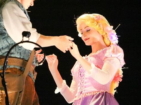 A Man Standing Next To A Woman In A Pink Dress On Top Of A Stage