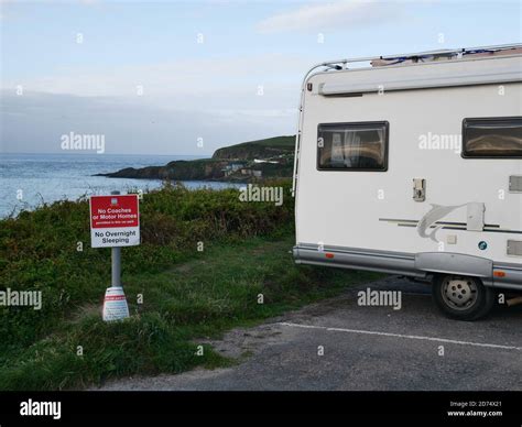 Motorhome campervan parked overnight camping in car park next to sign prohibiting overnight ...