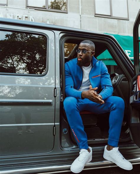 A Man In A Blue Suit Sitting On The Open Door Of A Vehicle With His