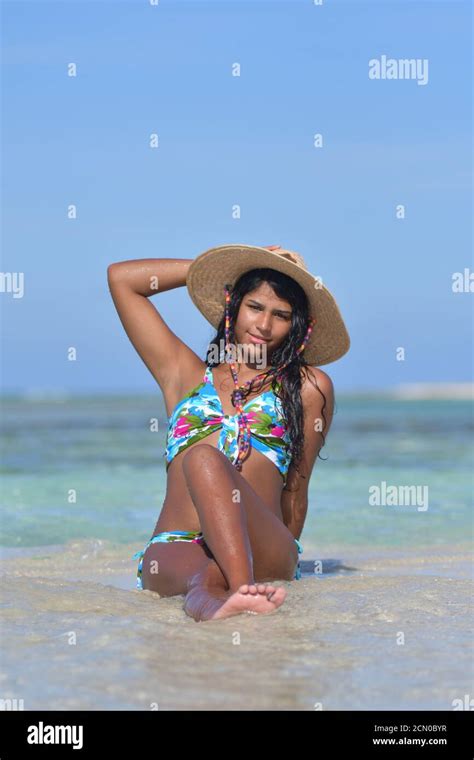 Hispanic Woman Siting On A Beach Wearing A Nice Bikini And Straw Hat