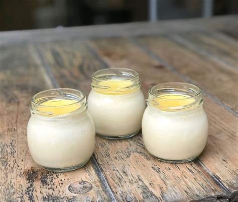 Three Small Jars Filled With White Liquid Sitting On Top Of A Wooden