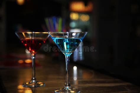 Two Martini Glasses Filled With A Colored Cocktails Standing On The Bar