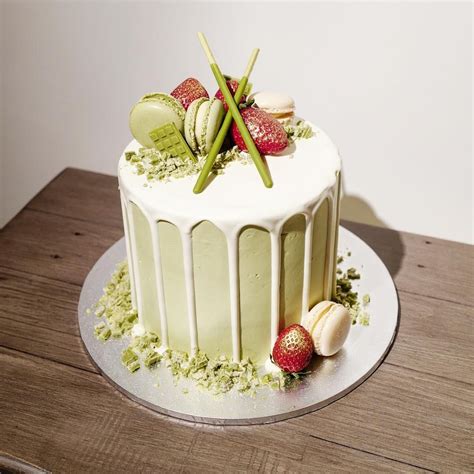 A Cake With White Frosting And Strawberries On Top Sitting On A Wooden Table