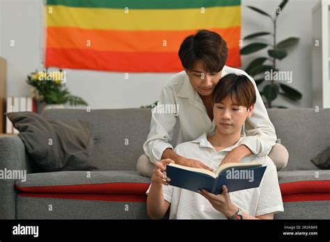 Image Of Passionate Gay Couple Sitting In Living Room And Reading Book