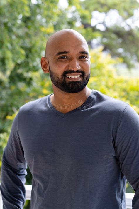 Portrait Of Smiling Bald Biracial Man With Beard Standing On Sunny