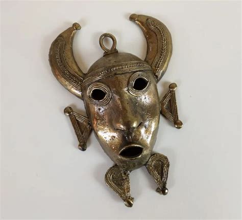 A Metal Mask With Horns And Eyes On A White Surface