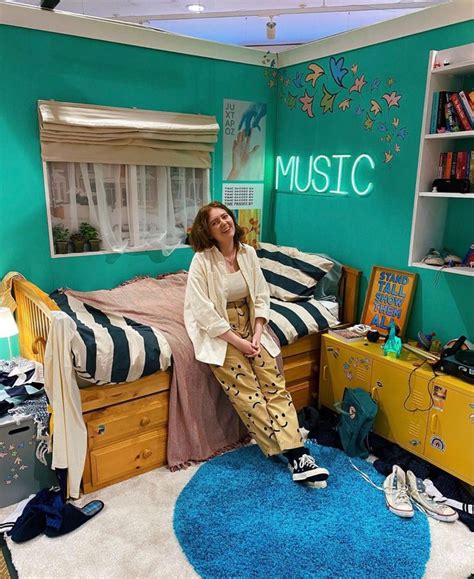 A Woman Sitting On Top Of A Bed In A Room With Blue Carpet And Green Walls