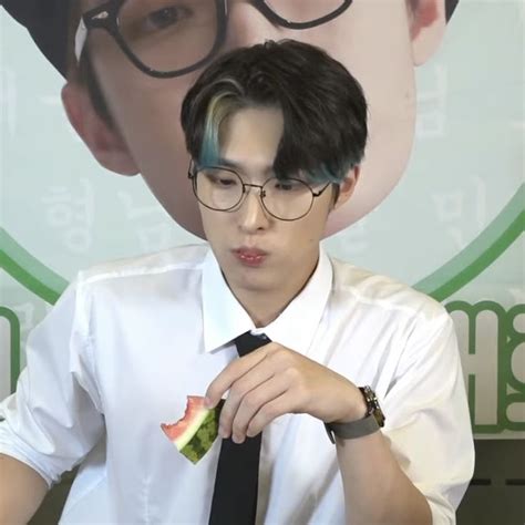 A Man With Glasses And A Tie Is Holding Food In Front Of His Face As He