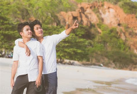 Retrato Homosexual Joven Pareja Asiática De Pie Señalando Algo Juntos En La Playa En Verano