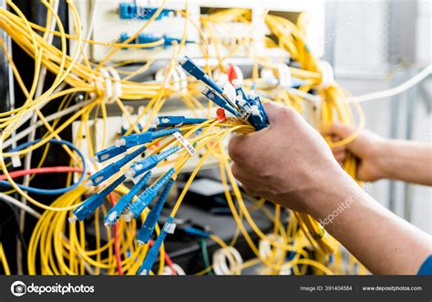 Network Engineer Working In Server Room Connecting Network Cables To