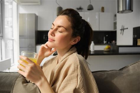 Premium Photo Gorgeous Brunette Woman Sitting On Sofa Drinking Glass Of Homemade Orange Juice