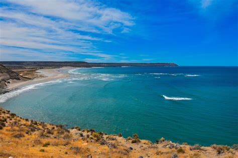 Oceano Lindo E Calmo Cercado Por Falésias Sob O Céu Azul Nublado Foto