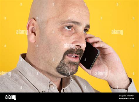 Cose Up Side Portrait Of Middle Aged Man Talking On Mobile Phone Bald