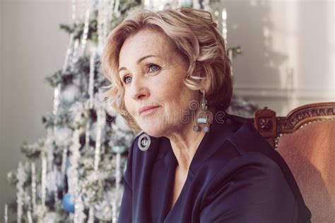 Elderly Smiling Happy Blonde Woman Is Sitting In An Armchair By The
