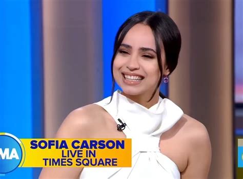 A Smiling Woman In White Dress On The Set Of An Ama Television Show