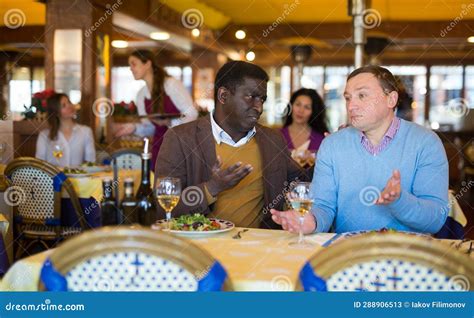 Dos Amigos Hombres Sentados En La Mesa En El Restaurante Y Hablando