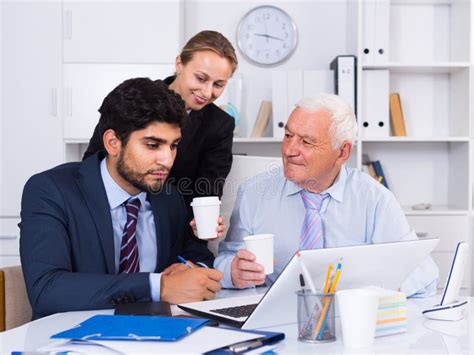 Employees Are Demonstrating Reports On Laptop To Mature Boss Stock
