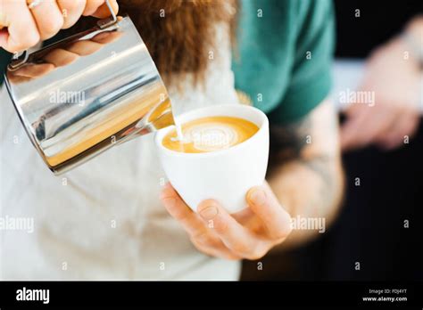 Closeup Portrait Of Barista Pouring Milk Into Cup Of Coffee At The