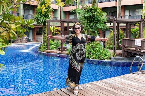 A Pretty Smiling Woman Near Swimming Pool Among A Beautiful Garden