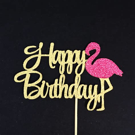 A Pink Flamingo Cake Topper With Happy Birthday Written In Gold Glitter