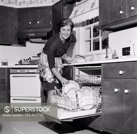 Mature Housewife Washing Dishes In Dishwasher SuperStock