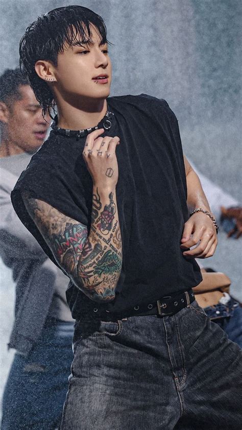 A Man With Tattoos On His Arm Standing In Front Of A Group Of Other People