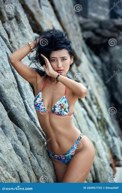 Beautiful Asian Girl In Bikini Posing On A Beach With Rocks Stock Image